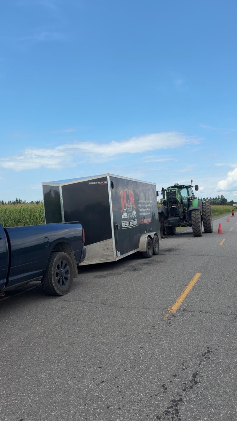 JCR truck and trailer stopped on a country road beside a Deutz-Fahr tractor, cones out