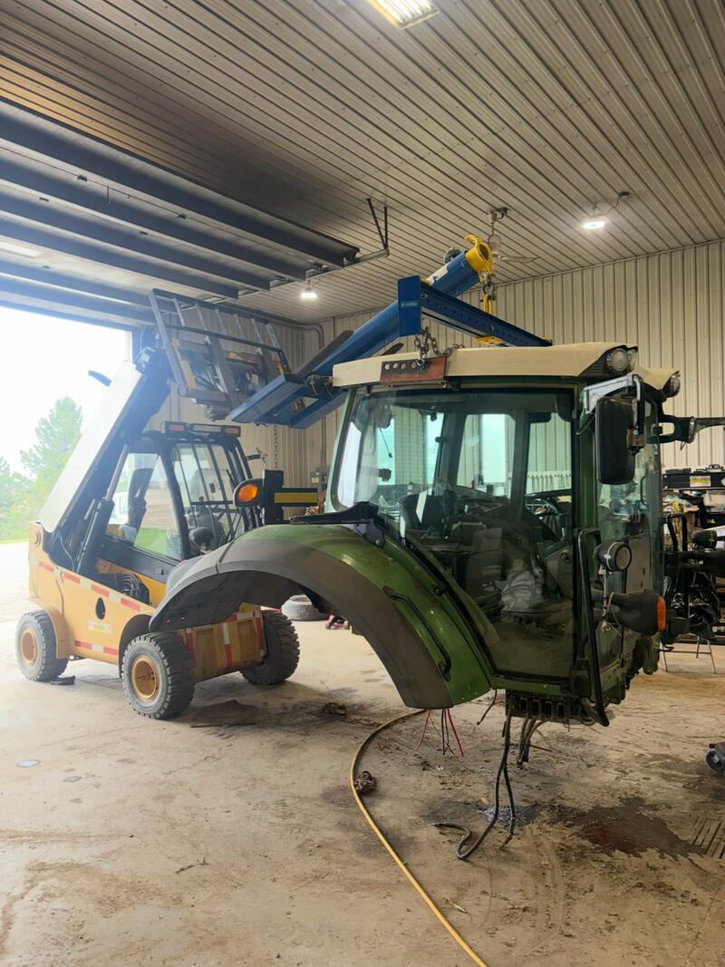 Tractor cab lifted off with a hoist in the shop