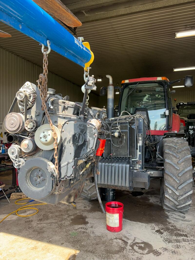 Diesel engine lifted out of a red tractor on a hoist